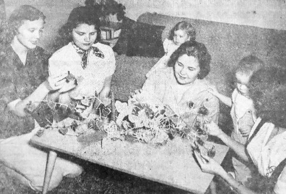 February 1958: VALENTINE DANCE Committee members of Sigma Delta chapter of Beta Sigma Phi here are working on decorations for their dance, at which Mrs. Jesse Dotson, second from left, was crowned chapter Valentine Sweetheart. Others pictured, from left, are Mrs. Don Cox, president; Mrs. Bob Jenson, dance chairman, and Mrs. Dick Moore. Interested observers are Donna Sue Cox and David Moore.