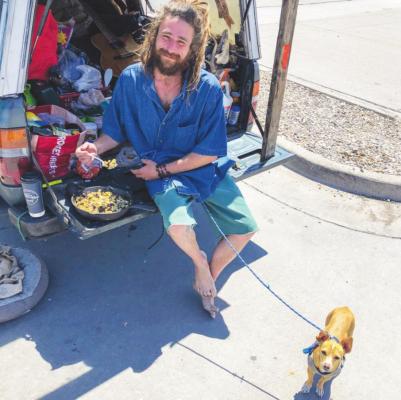 A man who introduces himself as Spiral Staircase reclines for some eggs with his dog Potato. The barefoot wanderer was also accompanied by his wife Toast. Photo by Jeremy Gonzalez