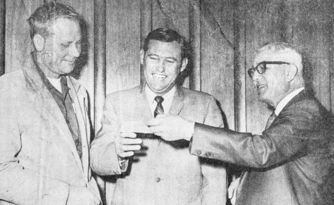 December 1969: BOOST FOR BOOSTERS – Panther Booster Club President Pat Gerald (center) happily accepts a check this week from Pioneer publisher George Baker. The check for $85.07 represents the unclaimed portion of the jackpot fund in the Pioneer football contest which ended last week. Looking on is head football coach Gene Mears, whose team will be honored along with “B” Team and Freshman players December 15 at a football banquet sponsored by the Booster Club.