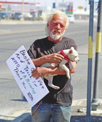 Ivan Johnson coddles his puppy “Pretty Girl” while holding tight to his sign against the strong winds on Saturday, March 13. Photo by Jeremy Gonzalez