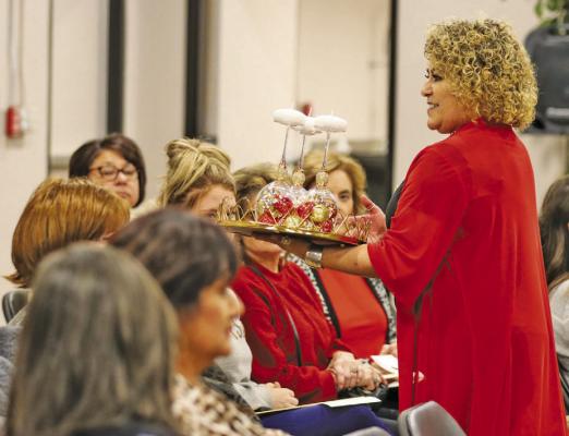 ABOVE: Monica Marrujo shows one of the items up for bid at Thursday’s Xi Zeta Lambda sorority holiday auction. RIGHT: Auctioneer Tom Ezell and Monica Marrujo discuss one of the items up for bid at Thursday’s Xi Zeta Lambda sorority holiday auction. Photos by Shawn Yorks