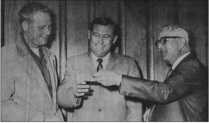December 1969 … Panther Booster Club President Pat Gerald (center) happily accepts a check this week from Pioneer publisher George Baker. The check for $85.07 represents the unclaimed portion of the jackpot fund in the Pioneer football contest which ended last week. Looking on his head football coach Gene Mears, whose team will be honored along with “B” team and freshmen players December 15 at a football banquet sponsored by the Booster Club.