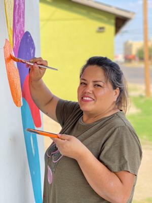 Erika Madrid puts the finishing touches on a mural in preparation for Barrio Fest and the celebration of Hispanic culture in the community. Courtesy Photo