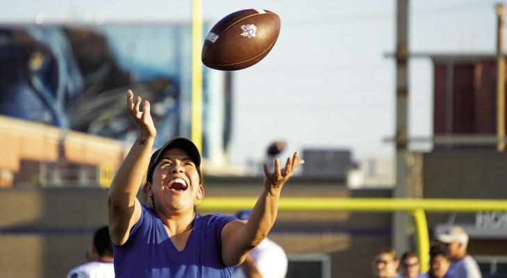 With a smile and eyes locked on the ball, a Panther mom practices her catching skills during the on-field portion of Football Moms 101, where mothers learned plays, ran drills, and experienced the game from their sons’ perspective. Photo by Tristian Barragan