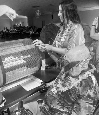 Catalina Riley helps Rev. Jim Miles draw a ping pong ball from the squirrel cage at last year’s Cruise Party. Courtesy Photo