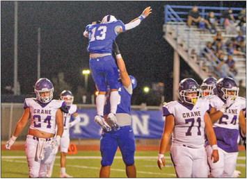 Cruz Rojas lifts teammate Isaiah Velasquez (13) in a celebration following Velasquez’s second touchdown score of Friday’s contest at Panthers Stadium against Crane. Photo by Nathan Heuer