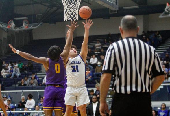 Fort Stockton’s Dominic Aguilar (21) scores a two-point basket in the paint over Pecos’ Ezekiel Saldana (0). The seniors were leading scorers for their respective teams. Photo by Nathan Heuer