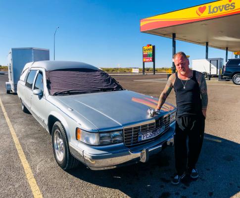 Traveler Smokey emerged from a hearse he named the Silver Ghost. With a cigar in his mouth he states his chrome duck hood ornament is a prop once used in movies. Photo by Jeremy Gonzalez