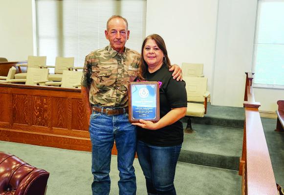 After 25 years of service, Frances “Minnie” Dominguez is stepping down as head librarian of the Iraan Public Library. Pictured here is Pct 3 Commissioner Mickey Jack Perry, awarding Dominguez for her years of devoted service to the county. Photo by Joh Covinton
