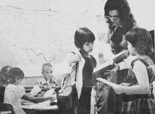 APRIL 1973-MRS.JERRY DOYLE, one of three team teachers at Comanche Elementary School assists two third graders with classroom assignments. Mrs. Doyle says the new concept being tried in her room frees her and the other teachers so they can give their students more individual atten-tion. (Pioneer photo)