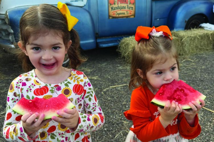 Emiliana and Victoria Rodriguez enjoy sweet watermelon from the Mandujano Brothers’ Produce Farms at the 6th Annual Pumpkin Patch 5K. Courtesy Photo by Veronica Mandujano